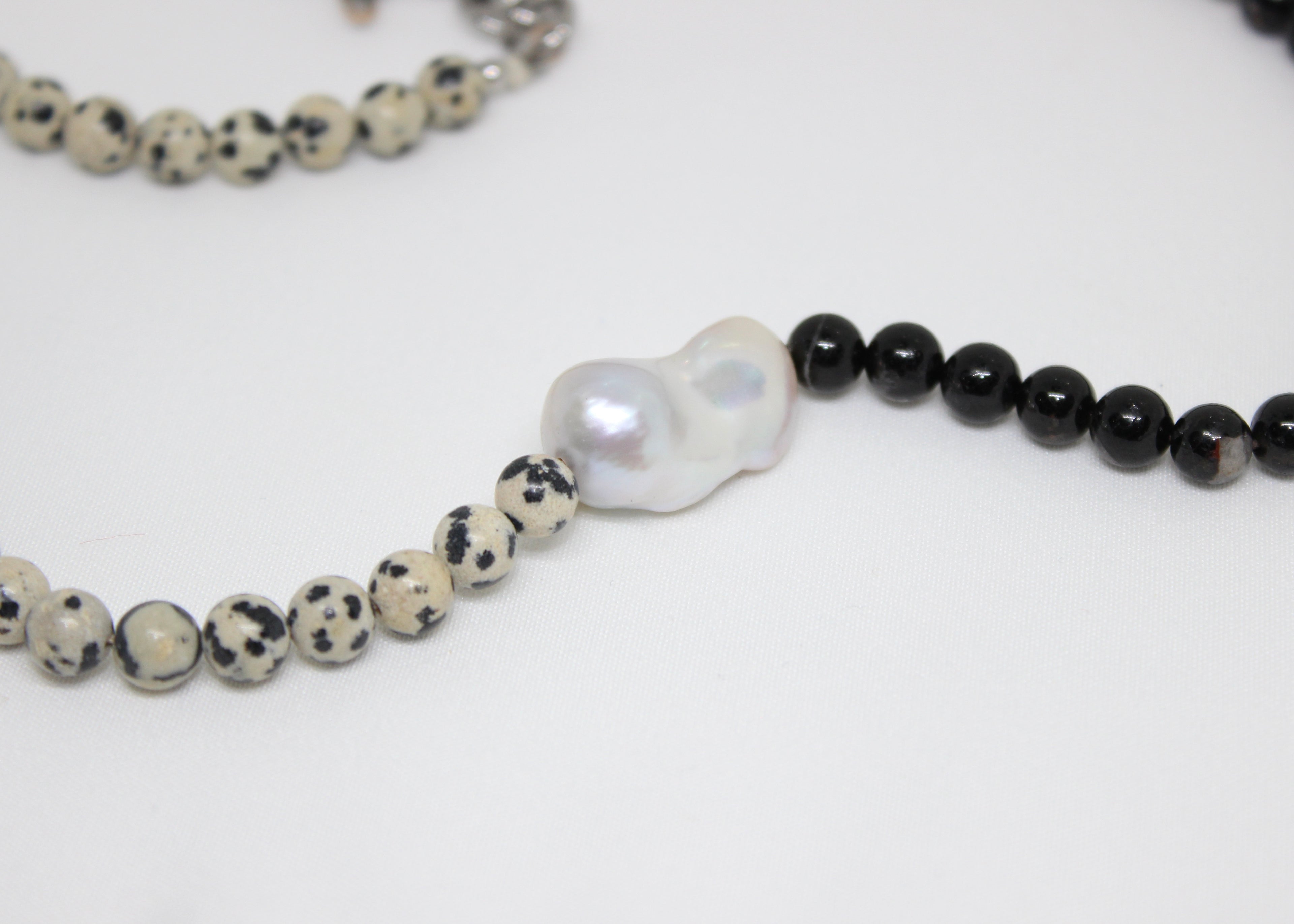 Beaded necklace with black tourmaline, dalmatian jasper, and freshwater pearl centerpiece.