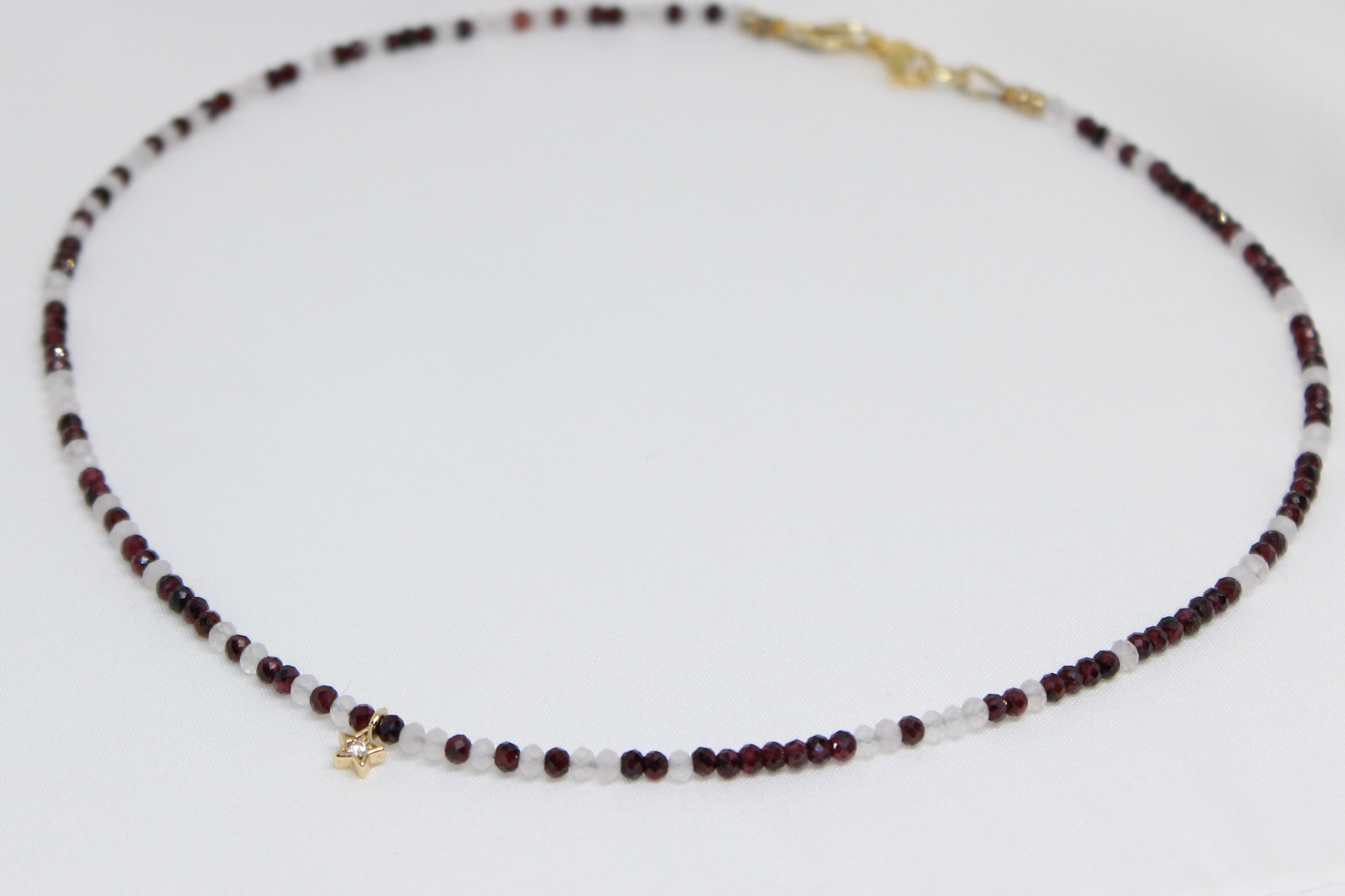Necklace with garnet and rose quartz beads and a gold star 