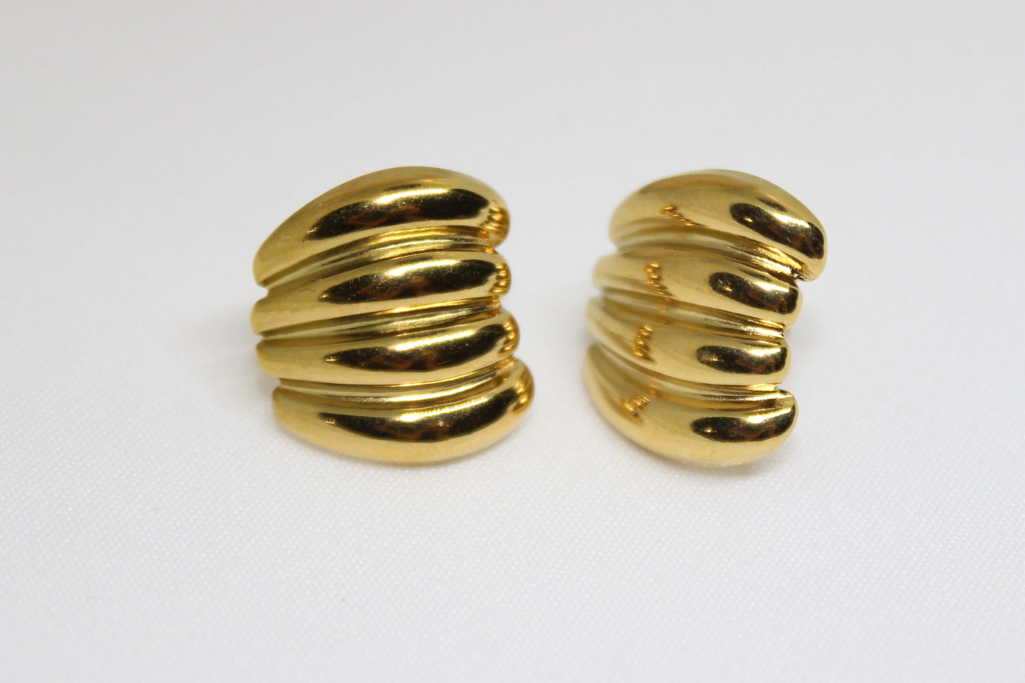 Pair of gold ribbed earrings on a white background