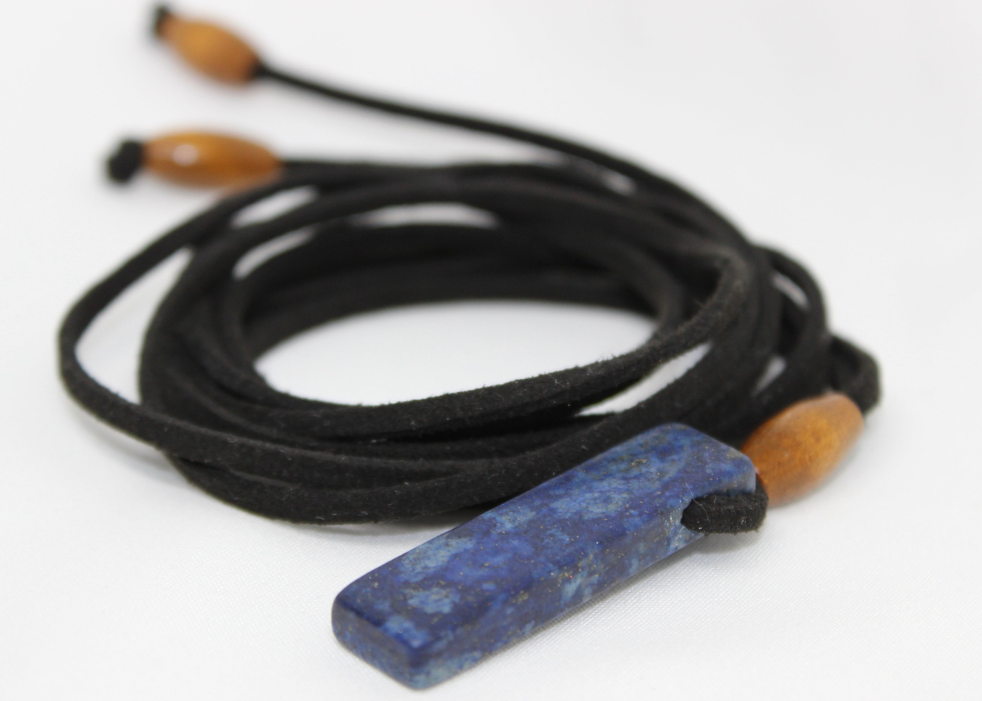 Adjustable necklace made with wood beads and a lapis lazuli pendant on suede cord, worn as necklace or choker.