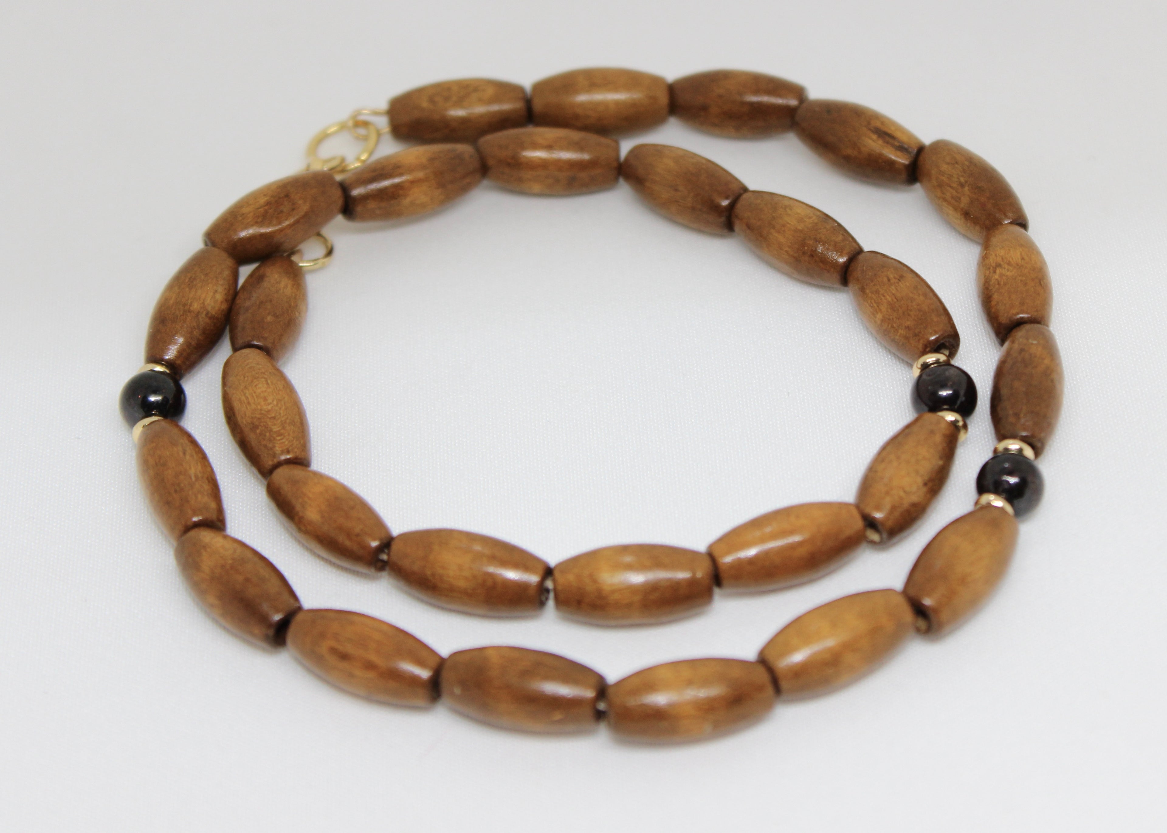 Grounding wood beads with garnet and gold accents. A necklace for strength, balance, and natural elegance in everyday wear.